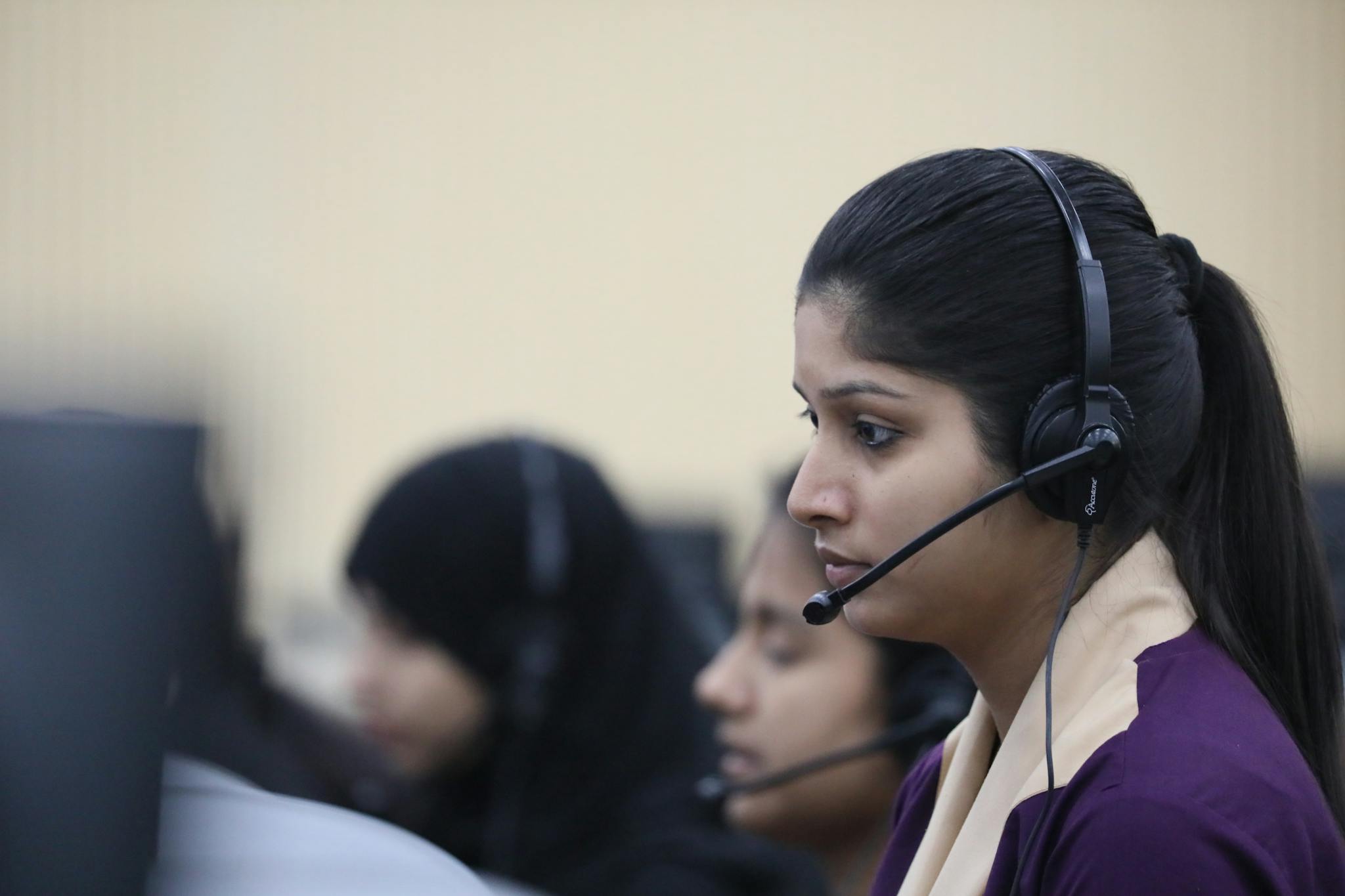 Young Asian woman working attentively as a call center agent in an office environment.